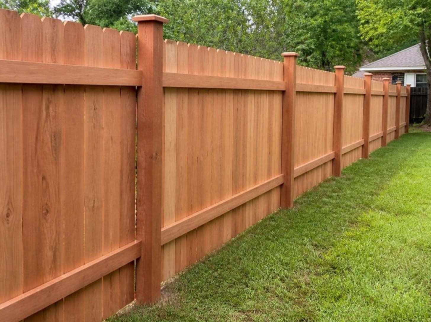 Reddish cedar privacy fence with square posts along a green backyard
