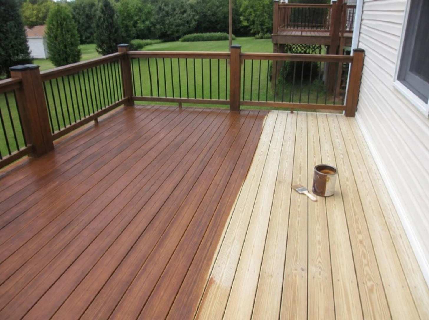 Pressure treated deck half stained brown and half bare, with a can of stain on the bare boards